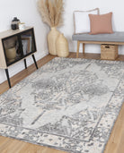 Alayah Ornamental Charcoal & Beige Rug in room with blonde flooring, wicker baskets and grey sitting bench