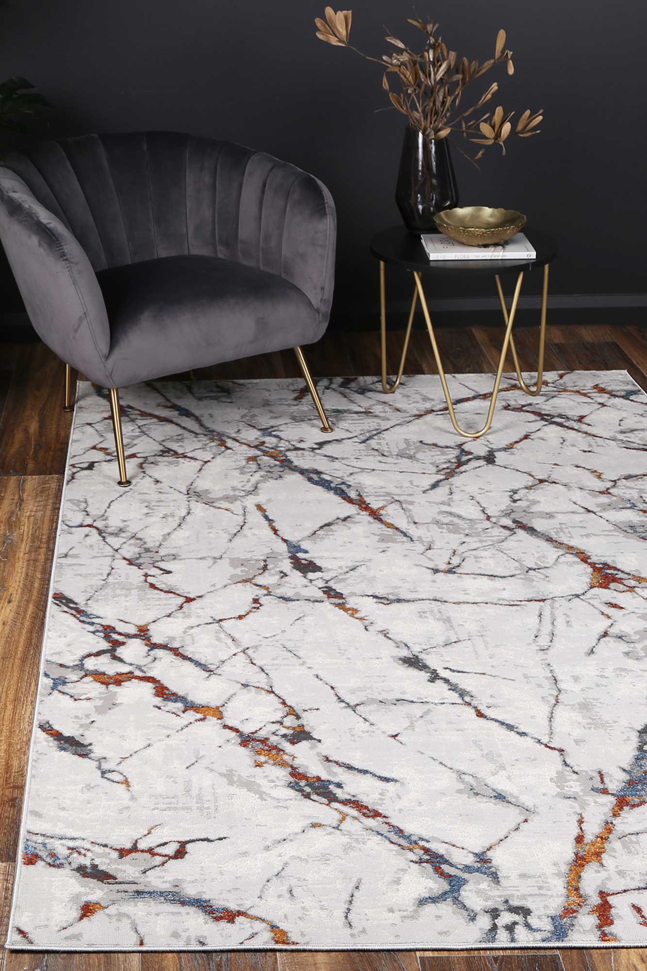 Almada charcoal and coloured Marble Rug in sitting room with armchair, dark stone side table with brass bowl